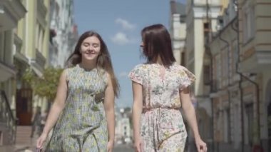 İki neşeli kadın, şehir caddesindeki alışveriş çantaları ile yürüyor. Birlikte vakit geçirmek zevk şık yaz elbiseleri giyen genç kızlar. Alışveriş yaşam tarzı konsepti.