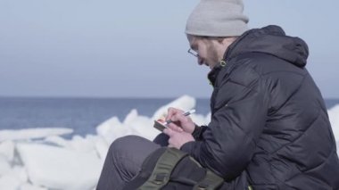 Yakışıklı sarışın sakallı adam bir defter içinde onun gözlem yazma buzların arasında oturuyor. Buzul üzerinde Polar Explorer.