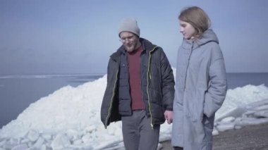 Yakışıklı sarışın sakallı adam el tutan güzel bir kadınla yürüyor. Arka planda karlı bir Kuzey veya Güney Kutbu muhteşem görünümü. Buzul keşfetmek turistler bir çift