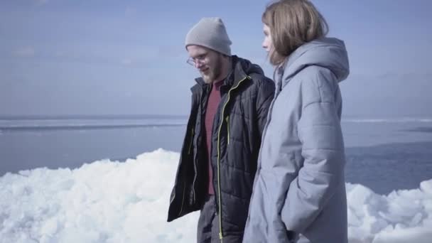 Roztomilý blonďatý vousatý muž, co chodí s pěknou ženskou. Úžasný pohled na zasněžený Severní nebo jižní pól na pozadí. Několik turistů prozkoumává ledovec — Stock video