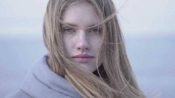 Close-up retrato de bela jovem loira com cabelos longos e olhos azuis olhando para a câmera. Mulher atraente de aparência escandinava na geleira — Vídeo de Stock