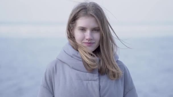 Portrait of cute confident young blond woman with long hair and blue eyes looking in the camera. Attractive woman of Scandinavian appearance on glacier — Stock Video