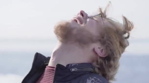 Πορτρέτο του αστεία μουσάτος άνθρωπος με γυαλιά κουνώντας τα ξανθά μαλλιά του ρίχνοντας το κεφάλι του πίσω, στη συνέχεια, κοιτάζοντας στην κάμερα χαμογελώντας κοντά. Θετικός τύπος, μπροστινή όψη — Αρχείο Βίντεο