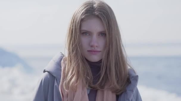 Portrait d'adorable jeune femme blonde confiante aux cheveux longs et aux yeux bleus regardant dans la caméra. Femme séduisante d'apparence scandinave sur glacier — Video