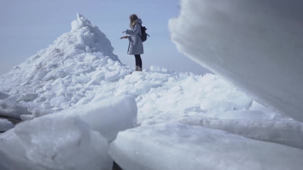 Kobieta turysta na tle próbuje sprawdzić z mapą, ale silny wiatr wieje co trudno zrobić. Niesamowity widok na śnieżny biegun północny lub południowy. Bloki lodu z bliska. Zimne piękno — Wideo stockowe