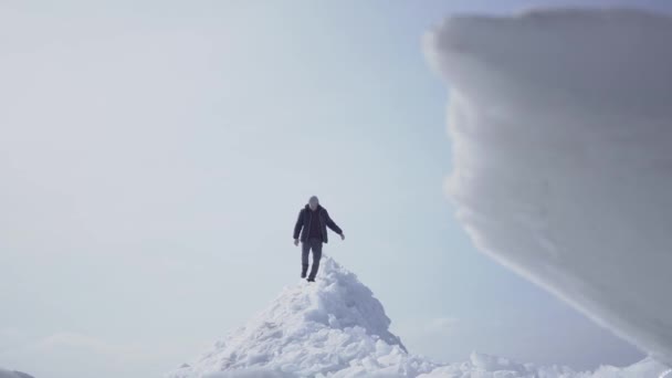 在冰川上行走的孤独的男性游客。雪的北极或南极的迷人景色。前景上的冰块关闭。冷美. — 图库视频影像