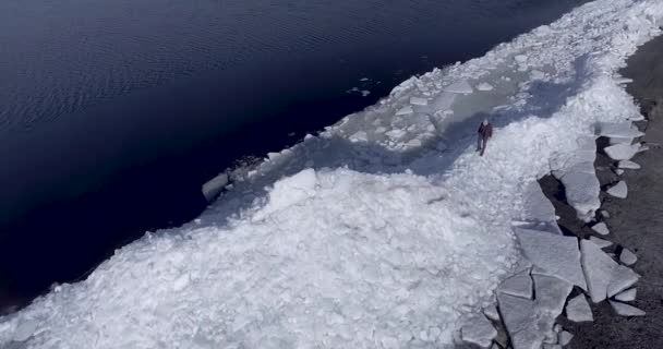Kış Denizi sahilinin yakınında buz buzulları üzerinde kalan genç aktif mutlu adamın hava dron görünümü. Drone görünümü. — Stok video