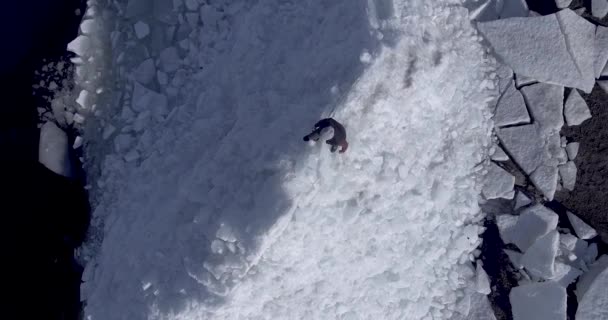 Vista aérea del dron del joven hombre feliz activo que permanece en los glaciares de hielo cerca de la costa del mar de invierno. Vista del dron . — Vídeo de stock