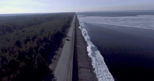 Vista aérea do dron das geleiras de gelo perto da costa do mar congelado do inverno, floresta com árvore do inverno e estrada com carros . — Vídeo de Stock