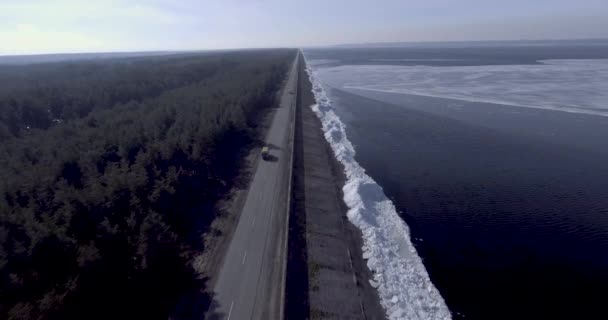 Aerial Dron utsikt över isen glaciärer nära kusten av vintern fryst hav, skog med vinter träd och väg med bilar. — Stockvideo