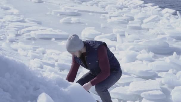 Fiatal jóképű ember geológus keresett valamit a hideg jég havazás gleccser mögött a téli tengeren. Lassított mozgás — Stock videók