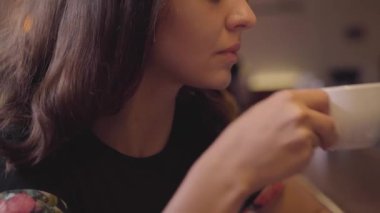 Bar tezgahında oturan kahvesinin tadını çıkaran çekici genç kadının portresi. Güzel kız modern kafe veya barda rahatlatıcı. Kahve molası