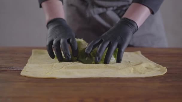Руки шеф-повара в черных кухонных перчатках делают шаурму крупным планом. Повар кладет помидоры и лук на питу. Вкусные арабские закуски — стоковое видео