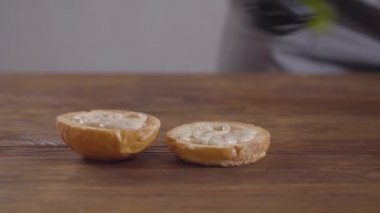 Siyah mutfak eldivenleri burger yakın çekim yapan şefin elleri. Bir hamburger topuzunun tek parçasına fesleğen yaprakları koyan aşçı. Lezzetli yemek hazırlama