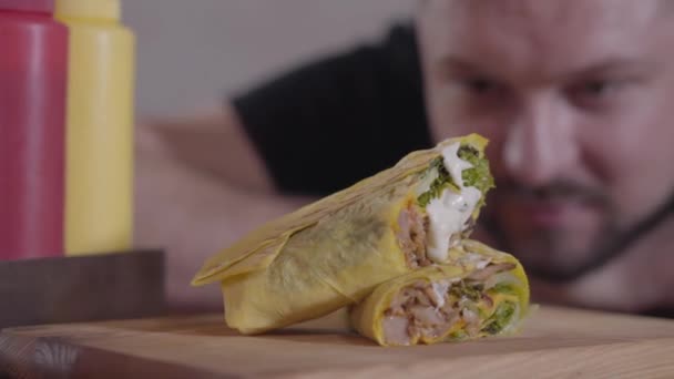 Välsmakande shawarma med sås liggande på trä ombord närbild. Suddig ansikte av en hungrig man tittar på shaurma i restaurangen redo att äta. Välsmakande arabiskt mellanmål — Stockvideo