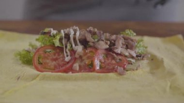 Shawarma yakın çekim yapma siyah mutfak eldivenleri şefin elleri. Dolgunun üzerine ağız sulandıran sos dökülür. Lezzetli atıştırmalık hazırlığı. Yavaş çekim.