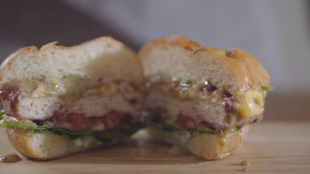 Close-up handen van Hamburger en saus stroomt uit. Lekker eten. Sappige verrukkelijke Hamburger liggend op de tafel. Slow Motion. — Stockvideo