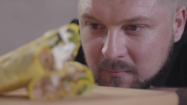 Νόστιμο σουβλάκι με σάλτσα που βρίσκεται στην ξύλινη σανίδα κοντά. Πρόσωπο ενός πεινασμένων που κοιτάζει το shaurma στο εστιατόριο έτοιμο να φάει. Νόστιμο αραβικό σνακ — Αρχείο Βίντεο