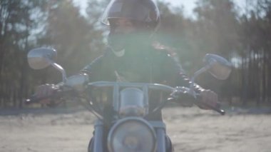 Portre güzel kız siyah kask giyen motosiklet üzerinde oturan uzağa bakıyor. Hobi, seyahat ve aktif yaşam tarzı. Bisikletçi dışarıda motosikletine biner. Eğlence ve motosiklet ile seyahat. Yumuşak ışık.