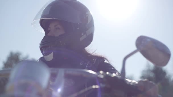 Retrato linda chica con casco negro sentado en la motocicleta mirando hacia otro lado. Hobby, viajar y estilo de vida activo. Motociclista en su moto al aire libre. Ocio y viajes en moto. Luz suave . — Vídeo de stock