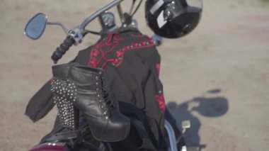 Yüksek topuklu ayakkabılar ve motosiklet yakın çekim üzerinde yatan siyah ve kırmızı elbise ile Çivili ayakkabılar. Nehir kıyısında direksiyonda kask olan motosiklet. Hobi, seyahat ve aktif yaşam tarzı