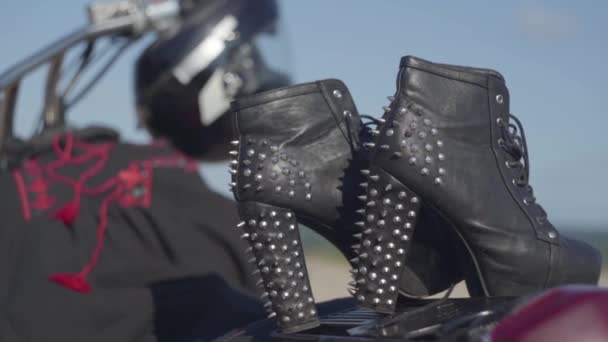 Spetsiga skor med höga klackar och svart och röd klänning liggande på motorcykel närbild. Motorcykel med hjälmen på hjulet på Riverbank. Hobby, resande och aktiv livsstil — Stockvideo