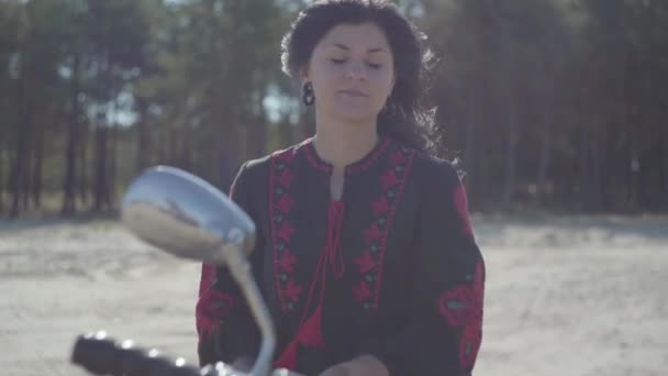 Une fille caucasienne est assise sur sa moto et porte un casque. Compétence femme dans une robe en cuir noir chevauchant une moto classique. Hobby, voyager. Loisirs et voyages en moto. Mouvement lent . — Video