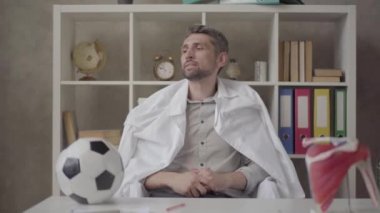 Yakışıklı pozitif bir adamın doktor cüppesini çıkarıp futbol izlemeye ve bira içmeye hazırlandığı portresi. Doktor iş gününü bitiriyor.