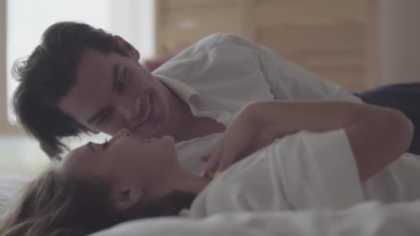 Man and woman laying on bed laughing. Concept of happiness and tenderness. Couple in love. — Stock Video