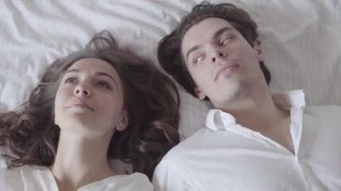 Sevimli adam ve kadın yatağa düşen ve sevgi ile birbirlerine bakıyor. Genç çift yatakta yatıyordu. İhale romantik ilişki