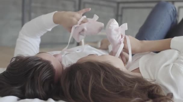 Overhead disparó feliz pareja acostada en la cama jugando con los niños de color rosa apuntan de cerca. Familia joven esperando a una niña. Concepto de relación tierna, personas enamoradas. Vista lateral — Vídeos de Stock