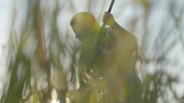 Roztomilá ženská, která sedne trávu na zelenou letní pole s kosou. Folklór, tradice. Pracujte v terénu. Farmář, pracující na pozadí východu slunce na jeho farmě. Opravdová Venkovská žena. — Stock video