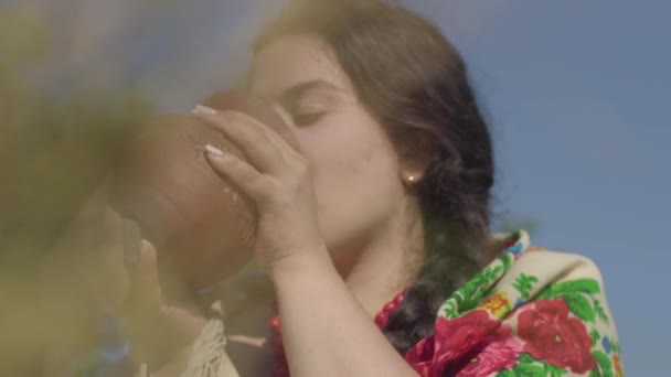 Mujer linda con sobrepeso disfruta de beber leche fresca de la jarra de barro al aire libre. Folclore, concepto de tradiciones. Mujer rural real . — Vídeos de Stock