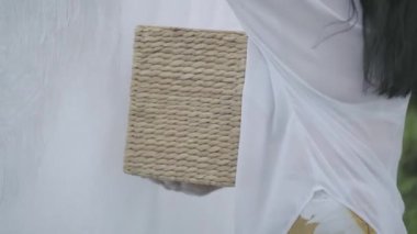 Tanınmayan olgun kadın bir çamaşır ipi açık havada beyaz giysiler asılı iken hasır sepet tutan. Yıkanıyor. Ev hanımı çamaşır yıkıyorum.