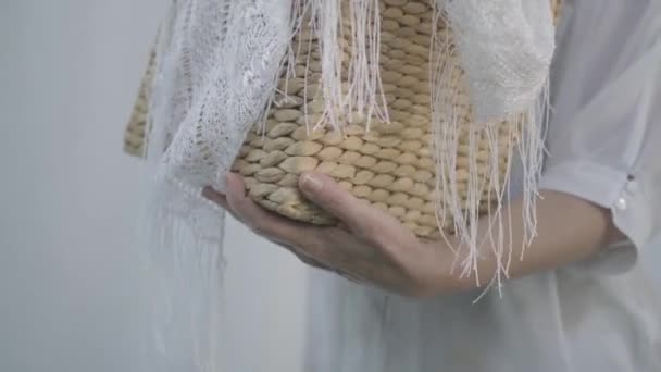 Крупним планом руки зрілої жінки тримають плетений кошик, підвішуючи білий одяг на контурі одягу на відкритому повітрі. Миття. Домогосподарка займається пранням — стокове відео