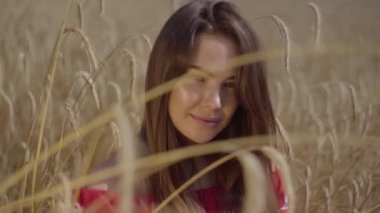 Portre büyüleyici genç kadın inanılmaz renkli güneş ışınları buğday alanında doğa ve güneş ışığı zevk. Sevimli kendine güvenen kız kameraya bakıyor. Kırsal yaşam tarzı. Gerçek insanlar serisi.