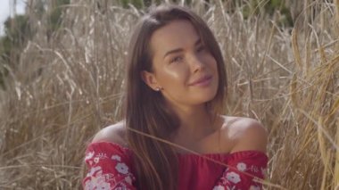 Genç sevinç kadın inanılmaz renkli güneş ışınları buğday alanında doğa ve güneş ışığı zevk. Sevimli kendine güvenen kız kameraya bakıyor. Gerçek insanlar serisi. Yavaş çekim.