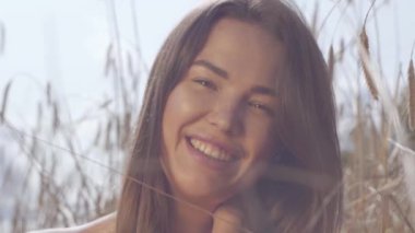 Portre genç sevinç kadın inanılmaz renkli güneş ışınları buğday alanında doğa ve güneş ışığı zevk. Sevimli kendine güvenen kız kameraya bakıyor. Gerçek insanlar serisi. Yavaş çekim.