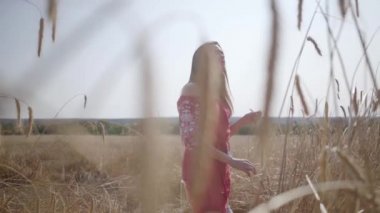 Güzel genç kadın inanılmaz renkli güneş ışınları buğday alanında doğa ve güneş ışığı zevk. Sevimli kendine güvenen kız kameraya bakıyor. Gerçek insanlar serisi.