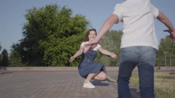 Kleine jongen rennen naar zijn oudere zus en knuffelen haar in het zomerpark. Vrije tijd buitenshuis. Vriendelijke relaties tussen broers en zussen. Zorgeloze kinderen met plezier samen — Stockvideo