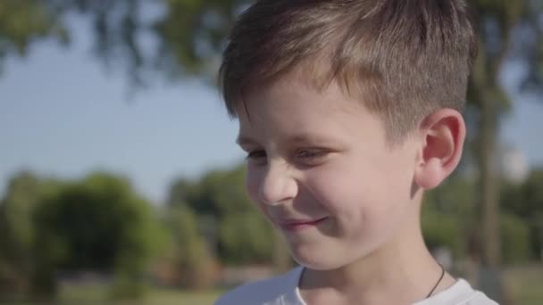 Portret van een schattige lachende jongen buitenshuis. Schattig kind tijd doorbrengen in het zomerpark. — Stockvideo