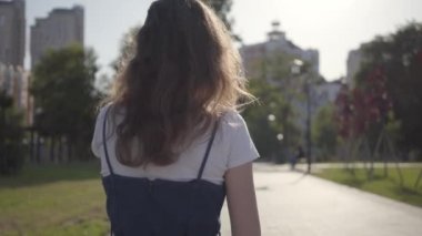 Küçük çocuk ablasına doğru koşuyor ve yaz parkında ona sarılıyor. Açık havada boş zaman. Kardeşler arasındaki dost ilişkileri. Carefree çocuklar birlikte eğlenmek