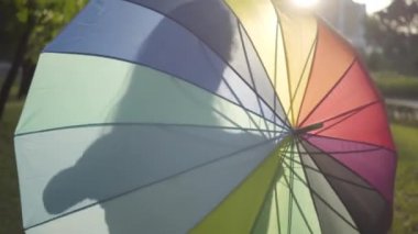 Çekici genç kız parkta çok renkli şemsiye dönüm. Yaz tatilinde. Genç Bayan sahip olan eğlence açık havada.