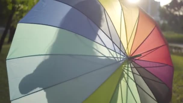 Jolie jeune fille tournant parapluie multicolore dans le parc. Loisirs d'été. Jeune femme s'amuser à l'extérieur .