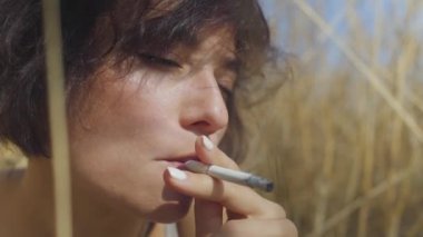 Kısa saçlı sigara ile şık kadın yakın yukarı portre sigarasız buğday alanı arasında oturan bakıyor. Kendine güvenen kaygısız kız açık havada. Gerçek insanlar serisi.