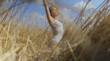 Kısa saç ile sevimli kadın vücut kıyafeti buğday alanında rahatlatıcı giyiyor. Kız kamera görünümlü ve poz doğa sahiptir. Kendine güvenen kaygısız kız açık havada. Gerçek insanlar serisi