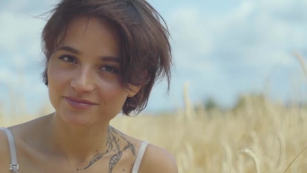 Portrait elegant woman with short hair relaxing on the wheat field. Girl enjoys nature looking and posing at the camera. Confident carefree girl outdoors. Real people series — Stock Video