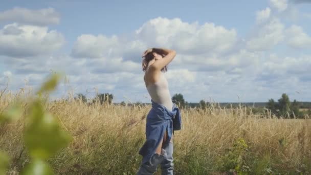 Милая женщина с короткими волосами в телесном костюме отдыхает на пшеничном поле. Девушке нравится смотреть на природу и позировать перед камерой. Уверенная беззаботная девушка на улице. Реальные люди — стоковое видео