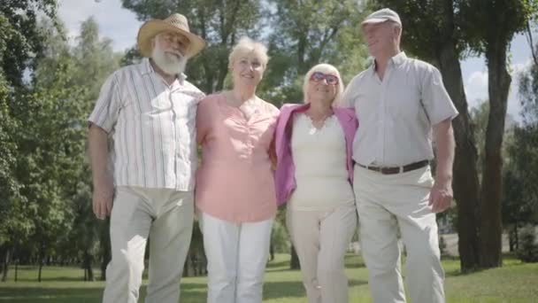 Dos parejas maduras lindas se reúnen en el parque juntos. Doble cita de parejas mayores. Amistosa compañía descansando al aire libre. Los ancianos y las mujeres se ríen alegremente. Personas mayores jubiladas sanas y alegres . — Vídeo de stock