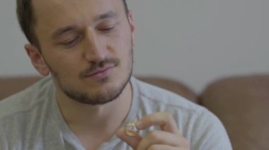 Evde oturan gülümseyen altın alyans tutan mutlu adam portresi. Adam kız arkadaşı için bir öneri yapacak ya da aile yaşamının hoş anları hatırlar.